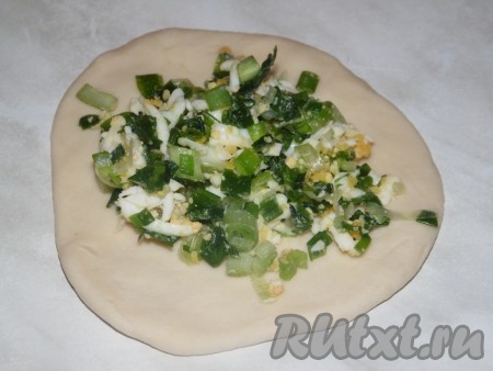 Когда тесто поднимется, обмять его руками и приступать к лепке пирожков. Отщипывая от теста небольшие кусочки, раскатывать их скалкой в круглые, не очень толстые лепёшечки (примерно с ладошку).&nbsp;На каждую из заготовленных лепёшек выложить немного начинки из зеленого лука и яиц.
