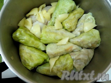 Дно посуды, в которой будем готовить голубцы, выстилаем капустными листьями, чтобы голубцы не подгорели. Плотно выкладываем голубцы. На них кладём кусочек сливочного масла. Между ними выкладываем кусочки перца, что улучшит вкус голубцов по-закарпатски.
