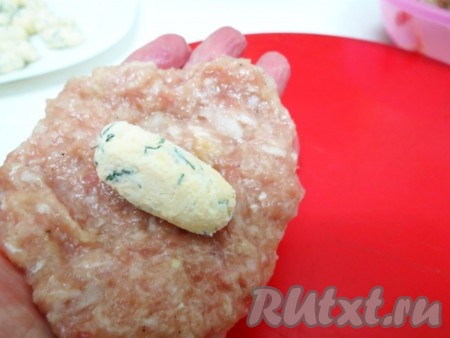 Разделываем получившуюся мясную массу на порционные кусочки. Берём один кусочек в ладошку и распределяем по ней. В центр выкладываем начинку и заворачиваем её.
