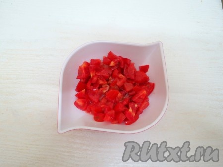 Вынимаем помидор из холодной воды и снимаем кожицу. Нарезаем очищенный помидор на мелкие кубики.