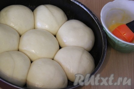 Накрыть форму с булочками полотенцем и оставить на 30-40 минут. Булочки увеличатся в размере. Желток слегка взбить, затем с помощью силиконовой кисточки смазать верх булочек желтком.