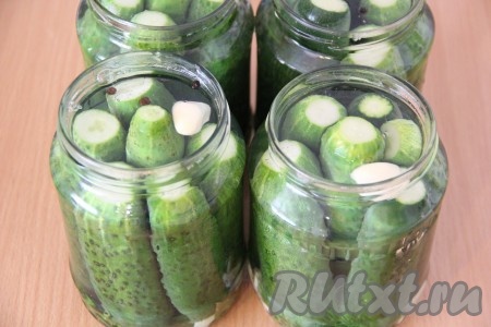 Воду влить в кастрюлю и поставить на огонь. Количество воды регулируйте сами, я мариную огурцы в большом количестве, поэтому и воды ставлю примерно 5 литров. Довести воду до кипения. Залить огурцы крутым кипятком. Прикрыть банки крышками и оставить на 10 минут.