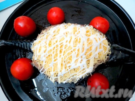 Посыпаем фаршированную скумбрию сверху сыром. Ну а теперь хочу поделиться своими выводами. Чтобы сыр не пересох во время запекания, я всегда сверху поливаю его сеточкой из майонеза. Но если вы противник майонеза, запекайте, использовав только сыр. Рядом с рыбой выложили помидоры, но это к рецепту не относится. Просто зять любит такие. Запекаем скумбрию, фаршированную грибами и сыром, в заранее разогретой до 190 градусов духовке в течение 20 минут.