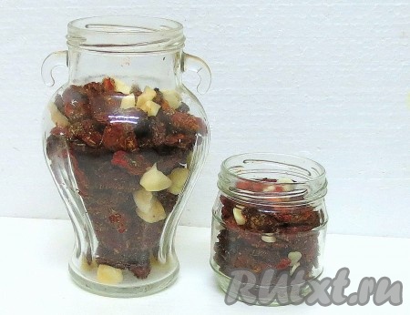 Стерилизуем банки и перекладываем в них вяленые помидоры, пересыпая ломтиками чеснока и иглами розмарина. Можно использовать листья свежего базилика.
