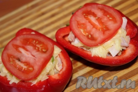 Половинки болгарского перца плотно нафаршировать подготовленной начинкой. Сверху выложить кружочки помидора.
