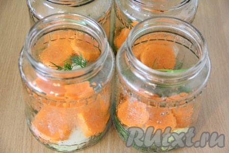 Банки под огурчики хорошо вымыть и простерилизовать любым способом. Выложить на дно банки колечки лука, моркови и веточку укропа.
