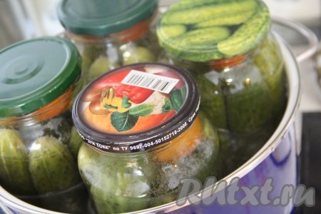 Взять достаточно большую кастрюлю, дно застелить полотенцем или тряпочкой, сложенной в 2-3 раза (застилать дно кастрюли нужно для того, чтобы банки точно не лопнули в процессе стерилизации). В подготовленную кастрюлю поставить банки. Влить достаточно горячую воду, она должна доходить до "плечиков" банок с огурчиками. Поставить кастрюлю с банками на средний огонь. После закипания воды немного уменьшить огонь, стерилизовать банки с огурцами на водяной бане 15 минут.&nbsp;