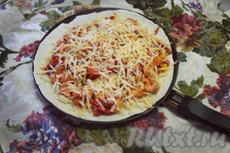 На сухую сковороду положить 1 лист тортильи, посыпать сыром, в частности у края, выложить половину начинки, снова посыпать сыром и закрыть сверху вторым листом тортильи.
