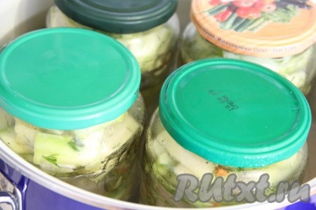 Дно большой кастрюли застелить полотенцем (благодаря полотенцу банки с кабачками не будут касаться дна кастрюли, а значит не лопнут в процессе стерилизации). Поверх полотенца поставить банки с кабачками, прикрыть их подготовленными крышками. Влить горячую воду в кастрюлю, чтобы она была по плечики банок. Поставить кастрюлю на средний огонь. Как только вода закипит, уменьшить огонь и стерилизовать банки 20 минут.