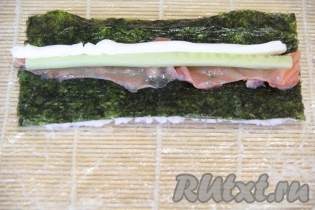  Аккуратно перевернуть лист нори вместе с рисом. Выложить начинку. Я положила кусочки рыбы и огурца. Творожный сыр переложить в пакет или кондитерский мешок, так удобнее формировать начинку. Выдавить творожный сыр.
