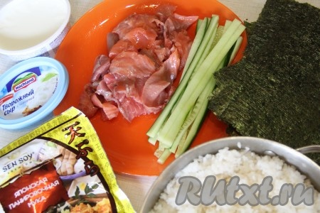 Нарезать огурец на длинные брусочки. Рис для приготовления суши хорошо промыть - до прозрачной воды (я обычно высыпаю рис в сито и промываю его под проточной водой). Затем переложить рис в кастрюлю, залить холодной водой, поставить на огонь, довести до кипения, уменьшить огонь и варить рис под крышкой на медленном огне до готовности (время варки и количество воды смотрите на упаковке). В сваренный рис влить рисовый уксус, хорошо перемешать и остудить рис до комнатной температуры.