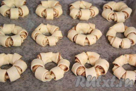 Противень для выпекания застелить пергаментом и слегка смазать растительным маслом. Выложить получившиеся бездрожжевые булочки с корицей на противень.