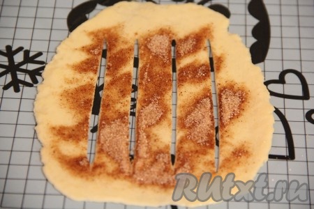 Из теста раскатать тонкую продолговатую лепёшку. Смазать лепёшку растопленным сливочным маслом и посыпать сахарно-коричной смесью. Сделать на тесте 4 разреза.