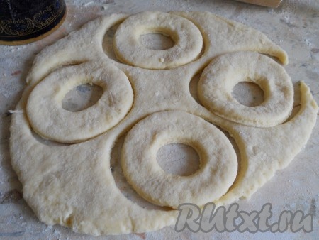 Тесто раскатать в пласт толщиной около 1 сантиметра на столе, чуть присыпанном мукой. Вырезать кружочки с помощью стакана, в середине вырезать кружочек меньшего диаметра (например, крышкой от пластиковой бутылки).