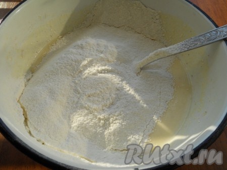 Всыпать 80 грамм просеянной муки и разрыхлитель, перемешать творожное тесто для пончиков ложкой.