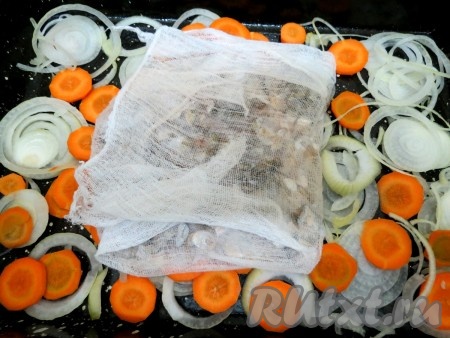 На дно противня нарезаем кольцами 2 луковицы и 2 моркови. В марлечку выкладываем чешую, заворачиваем марлечку и также выкладываем на дно противня.
