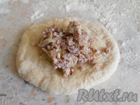 Разделить тесто на 4 части, из каждой скатать колбаску, которую нарезать на части (вес каждой части 60-70 грамм). Каждую часть теста скатать в шарик и приплюснуть в лепёшку. На середину лепёшки поместить 1 столовую ложку мясной начинки, сформировать пирожок