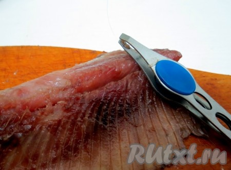 По позвоночнику разрезаем рыбу вдоль. Пинцетом удаляем косточки. У нас получится 2 филе сельди без косточек.