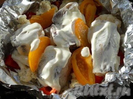 Между рыбой поместить дольки помидора и смазать обильно кусочки хека жирной сметаной. Влить немного воды (30 мл).
