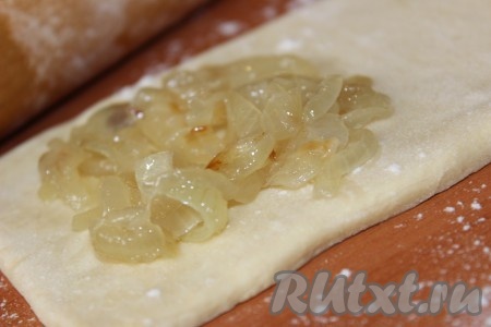 Каждую из частей теста слегка раскатать в одном направлении. На один край этой части теста выложить обжаренный лук.
