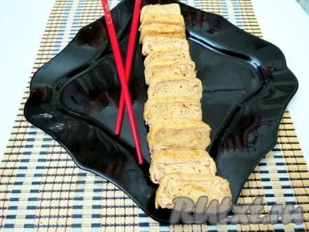 Придаём руками получившемуся рулету прямоугольную форму. Нарезаем на порционные кусочки и угощаем своих родных и близких очень вкусным японским омлетом "Тамагояки". По желанию, его можно украсить, например, кунжутом и растопленным шоколадом.