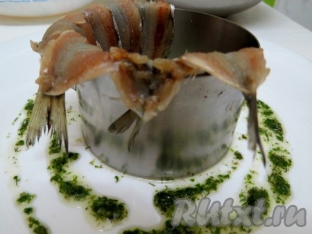 Берём кулинарное кольцо. Если у вас его нет, используйте баночку от консервов, удалите у неё донышко. Ставим кольцо в центр тарелки. Внутрь выкладываем внахлёст салаку спинками внутрь. Хвостовая часть должна немного свисать.
