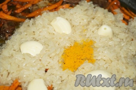 Рис промыть, чеснок очистить и разделить на зубчики. Добавить рис к поджаренным куриным сердечкам, моркови и луку. Сверху выложить дольки чеснока, добавить воду, куркуму, довести до кипения (накрывать крышкой не надо). Когда будущий плов закипит, накрыть крышкой, уменьшить огонь до минимума и готовить минут 40-50, не перемешивая, до готовности.
