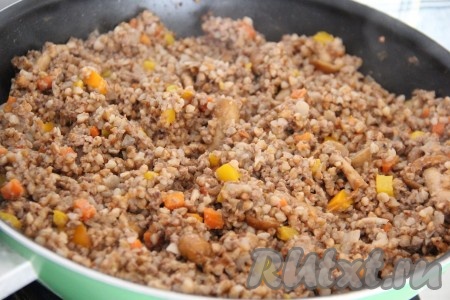 Всё хорошо перемешать, накрыть сковороду крышкой и убавить огонь до минимума. Готовить гречку с фаршем и грибами в течение 30-35 минут.