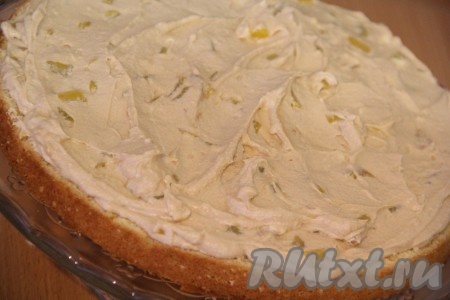 Затем большой корж выложить на плоскую тарелку (или подставку под торт) срезом вверх. Нанести на корж часть крема и равномерно распределить его по поверхности коржа.