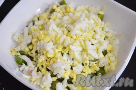 Далее разложить натертые яйца, посолить, нанести сеточку из майонеза.
