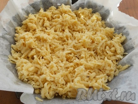 Форму для выпечки (я взяла форму диаметром 22 сантиметра) застелить пергаментом, смазать немного растительным маслом. Достать из морозилки одну часть теста и натереть его на крупной тёрке прямо в форму.