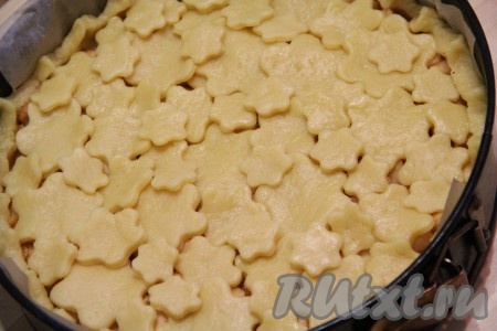 Выложить цветочки из теста поверх начинки. Поставить яблочный пирог в сметанной заливке в разогретую духовку и выпекать при 180 градусах примерно 40 минут.