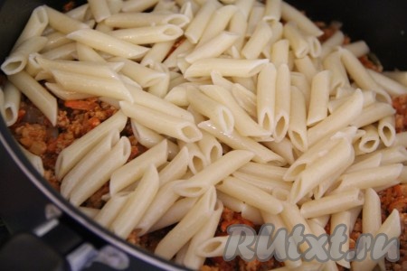 Добавить макароны в сковороду с фаршем и тщательно перемешать.