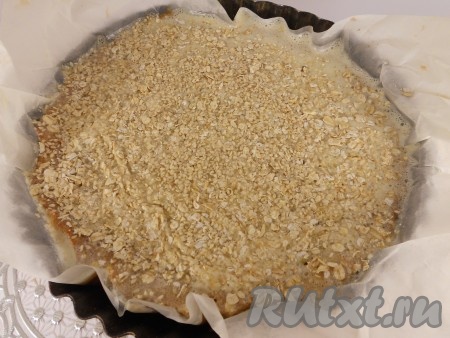 Добавить в яичную смесь растопленное и охлажденное сливочное масло, перемешать. Пирог достать из духовки и залить его заливкой. Сверху посыпать кунжутом, овсяными хлопьями и 1 столовой ложкой сахара.
