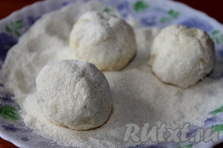 Сформировать из теста шарики величиной с грецкий орех. Чтобы шарики легко формировались, руки необходимо смачивать водой. Обвалять шарики в манке.
