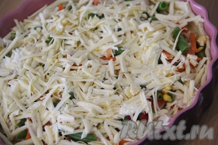 Сыр натереть на крупной тёрке. Щедро посыпать верх пирога сыром.