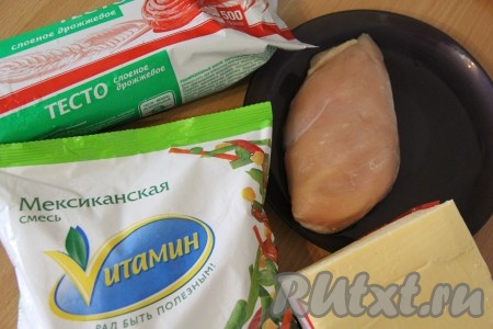 Подготовить продукты для приготовления пирога. Тесто заранее достать из холодильника и разморозить при комнатной температуре. Куриную грудку отварить в подсоленной воде до готовности, а затем слегка остудить.
