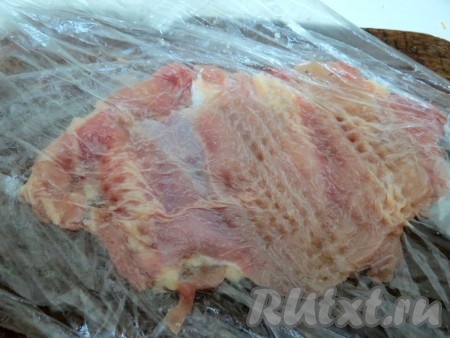Полученное куриное филе кладём между двумя слоями пищевой плёнки и слегка отбиваем с двух сторон.
