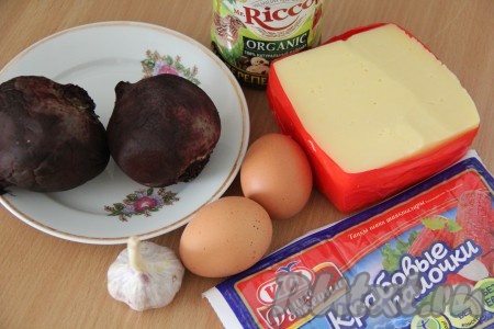 Подготовить продукты. Свеклу вымыть, не очищая от кожуры, выложить в кастрюлю, полностью залить водой, отварить до готовности (готовые корнеплоды должны легко прокалываться ножом, в зависимости от сорта свеклы на варку с момента закипания воды потребуется минут 45-70). Варёную свеклу переложить на тарелку, дать полностью остыть. Сварить вкрутую яйца (варить 10 минут с момента начала кипения воды), а затем полностью остудить. Если крабовые палочки заморожены, их нужно будет полностью разморозить при комнатной температуре, после этого снять упаковку.
