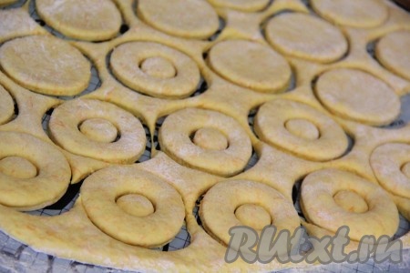 Скалкой раскатать тесто в пласт толщиной 1 сантиметр и с помощью&nbsp;тонкого стакана вырезать пончики. Середину пончика можно вырезать с помощью пробки от пластиковой бутылки.