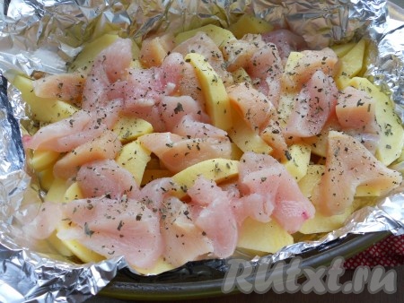 На картофель выложить куриное филе, нарезанное длинными кусочками. Посыпать все специями, базиликом, сушеным чесноком, черным перцем.
