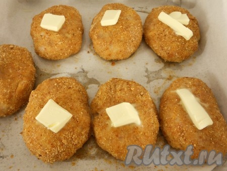 Духовку разогреть до 180 градусов и поместить в нее котлеты из курицы и свинины. Запекать 15 минут, после чего котлеты достать и на каждую котлетку поместить по небольшому кусочку сливочного масла. Вернуть котлеты в духовку еще на 15 минут.