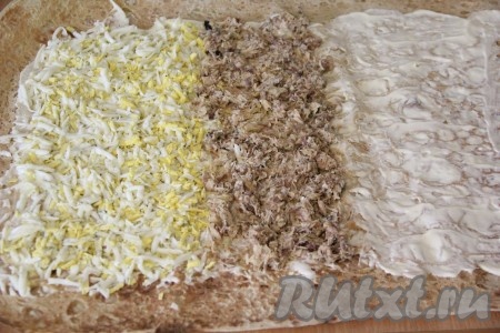 Рядом с яйцами выложить на лаваш рыбные консервы и разровнять. 