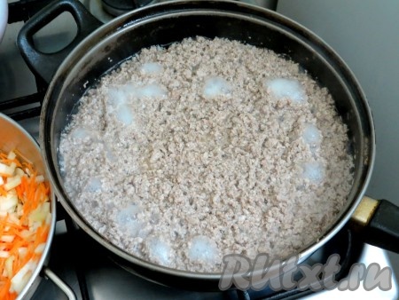 Фарш выкладываем на холодную сковороду без жира, добавляем стакан холодной воды и вилкой тщательно разбиваем все комочки. У нас получается кашица. Включаем средний огонь и перемешиваем быстро вилкой. Масса закипит и на среднем огне, время от времени помешивая, продолжаем готовить фарш. Как только вода испарится, добавляем растительное масло и продолжаем жарить. Эта процедура займёт минут 20. Фарш должен слегка стать золотистым. Пока жарится фарш, отвариваем макароны в двух литрах посоленного кипятка, в соответствии с инструкцией на упаковке, затем лишнюю воду сливаем.
