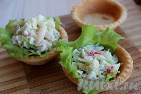 Наполнить крабовым салатом тарталетки. На дно тарталеток я выложила листья зеленого салата.

