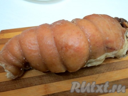 Через полтора часа рулет из подчеревка вынимаем из кастрюли с водой, снимаем с него плёнку выкладываем на противень. Жидкостью из пакета для запекания, выделившейся во время варки, поливаем рулет. Жидкости будет немного, но она поможет сохранить сочность мяса. Отправляем противень с рулетом в заранее разогретую духовку минут на 20, чтобы корочка немного зарумянилась. Температуру выставляем 230 градусов. Запеченное мясо достаём из духовки, даём остыть, снимаем нитки. Желательно остывшее мясо отправить на ночь в холодильник, тогда оно будет нарезаться тонкими пластами.
