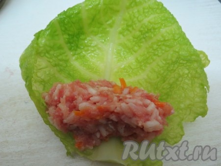 У капустных листьев вырезаем утолщения. На каждый лист выкладываем по 1,5-2 столовых ложки начинки.
