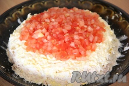 Выложить измельченный помидор поверх яичного слоя. Формировать из продуктов высокую горку.