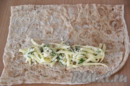  На лаваш ближе к одному из краёв квадрата выложить часть сырной начинки, как на фото.
