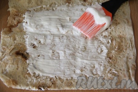 Лаваш нарезать на квадратики. Смазать серединку лаваша сметаной. 